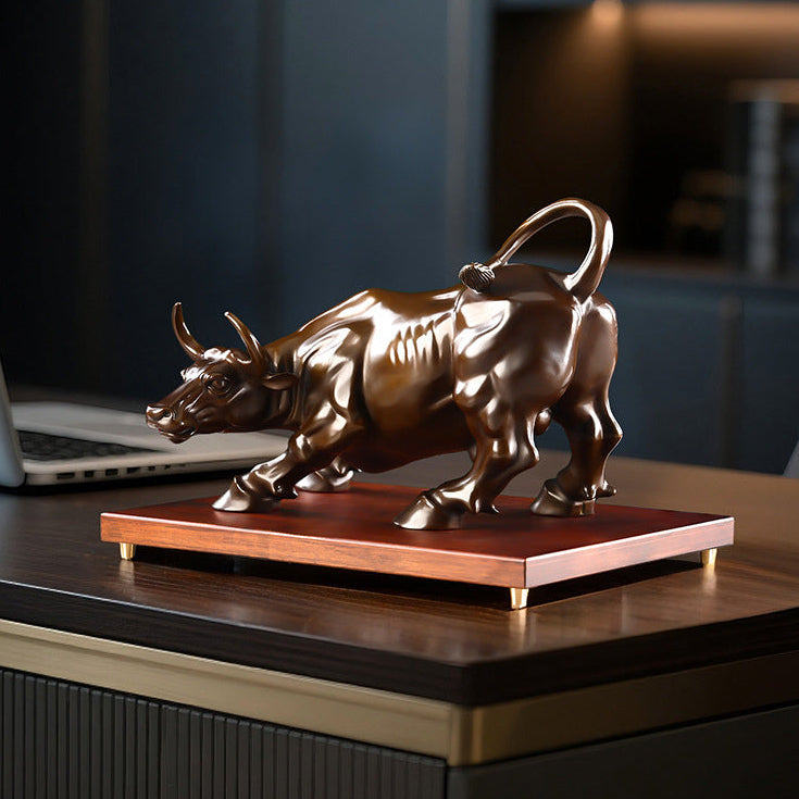Solid brass bull sculpture displayed on a wooden desk in a private study.