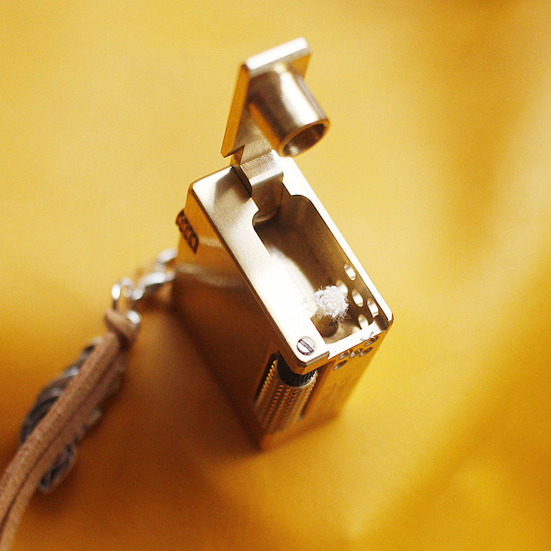 Vintage brass oil lighter keychain hanging, refillable petrol lighter close-up