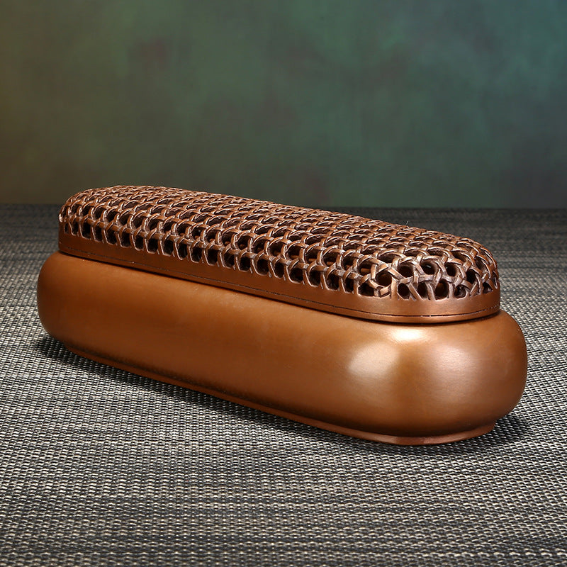 Brown decorative box with woven lid on a textured surface