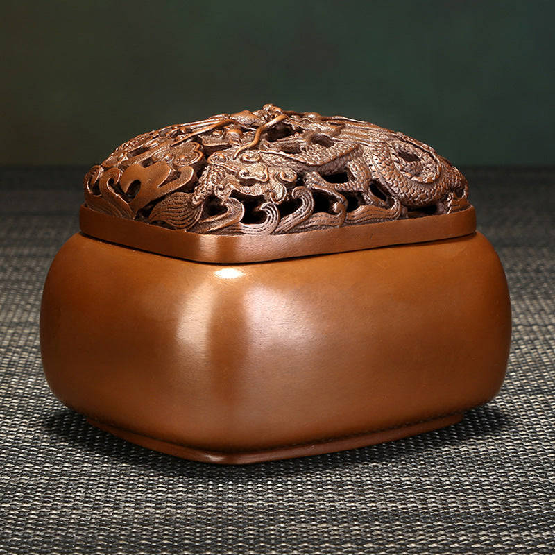 Decorative brown incense burner with intricate designs on a textured surface
