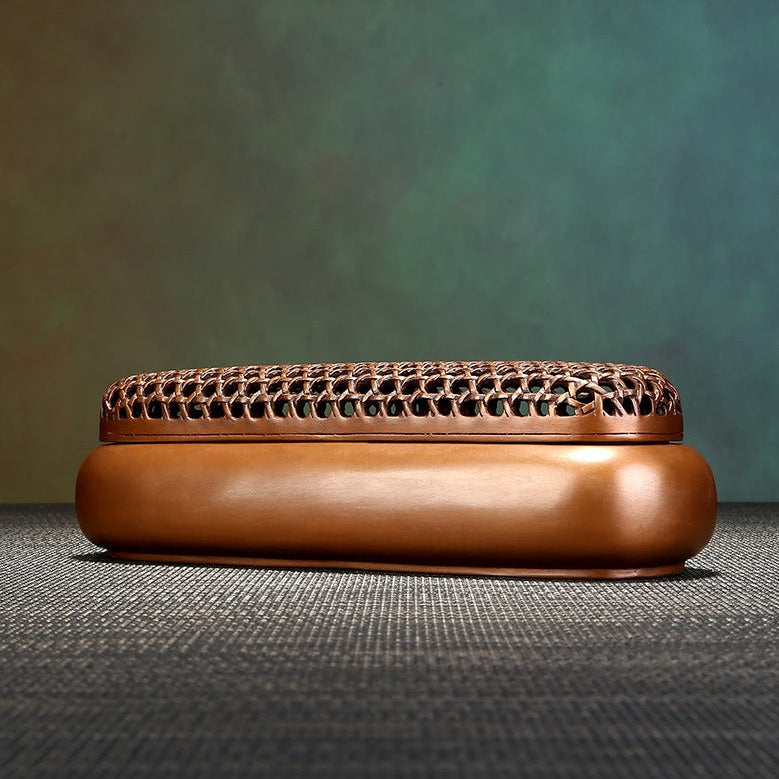 Brown ceramic incense burner with intricate design on a textured surface