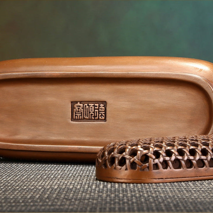 Solid brass incense burner with gentle smoke in a private study.