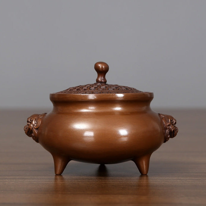 Bronze incense burner with lion-head handles displayed in a private study