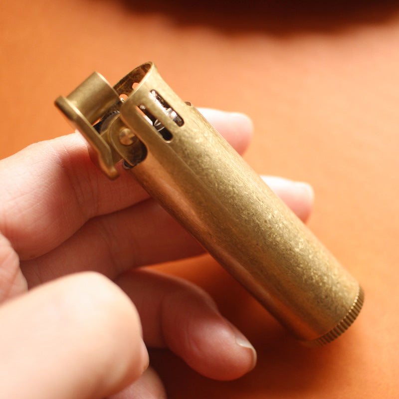Vintage brass oil lighter with antique finish resting on leather, refillable petrol lighter
