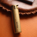 Vintage brass oil lighter with antique finish resting on leather, refillable petrol lighter
