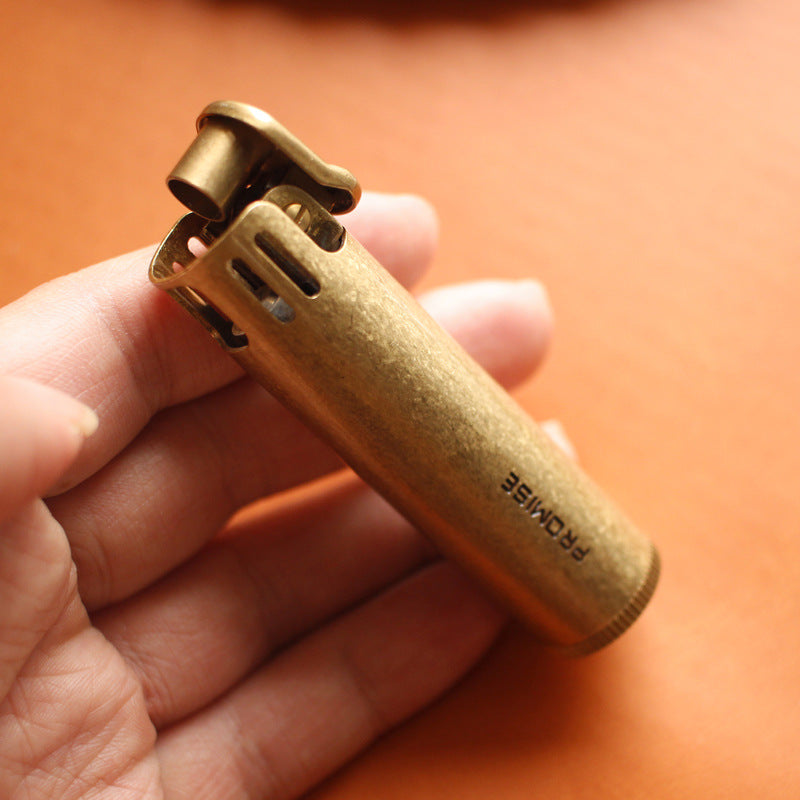 Vintage brass oil lighter with antique finish resting on leather, refillable petrol lighter