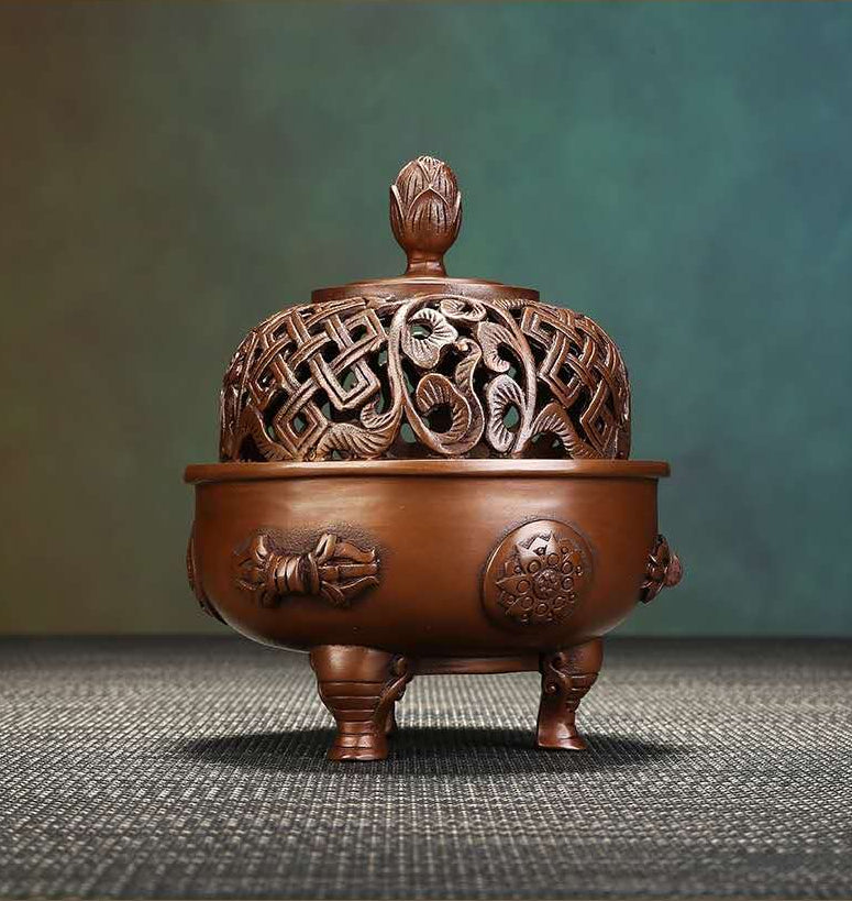 Decorative wooden incense burner with intricate carvings on a textured surface.
