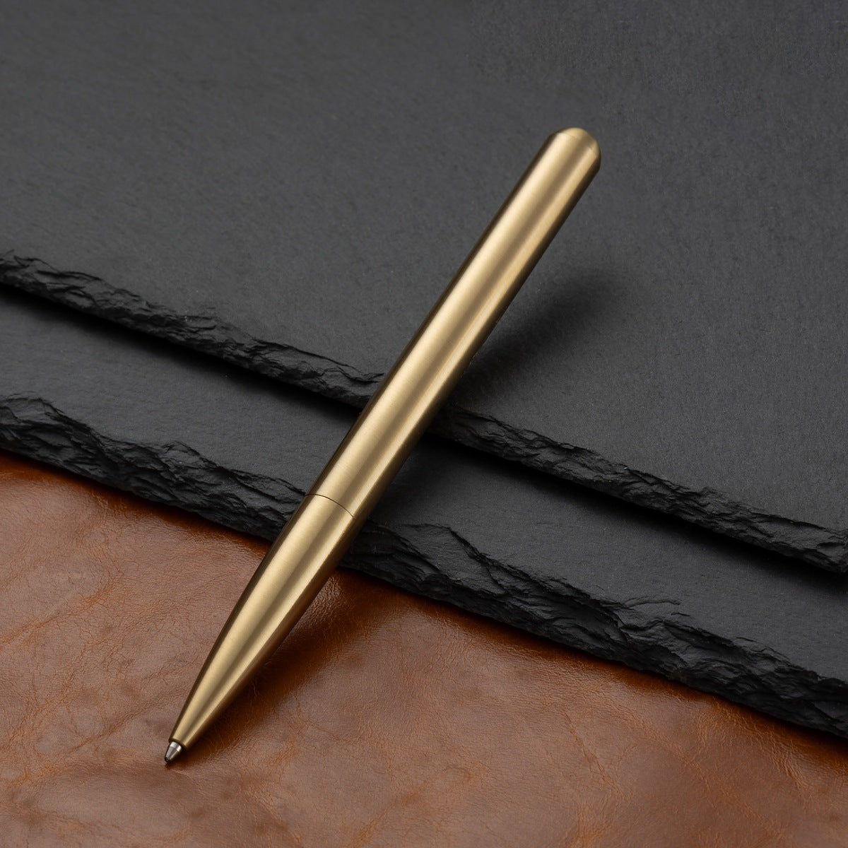 Minimal brass writing pen styled on a leather desk with vintage paper elements.
